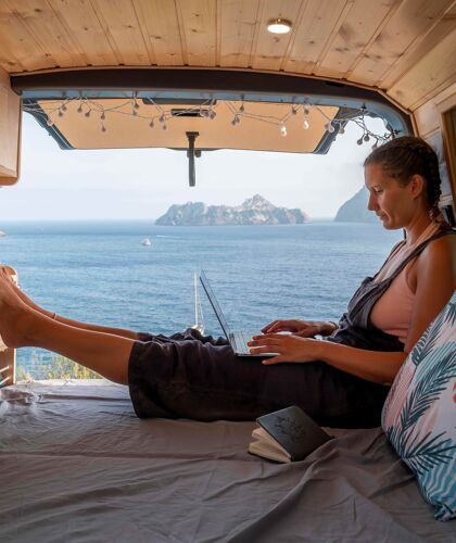 jonge-vrouw-gebruikt-laptop-achterin-zelfbouw-camper