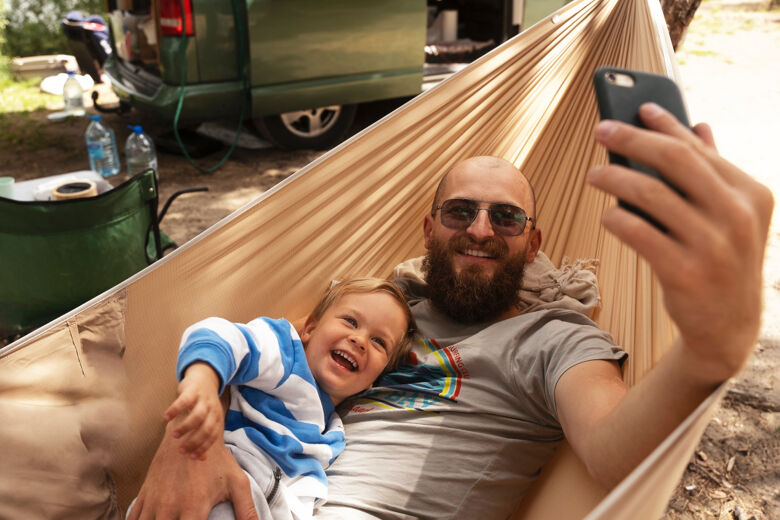 high-angle-man-taking-selfie-with-kid-hammock